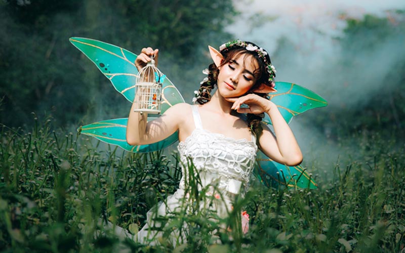 A girl in white dress wearing green fairy wing